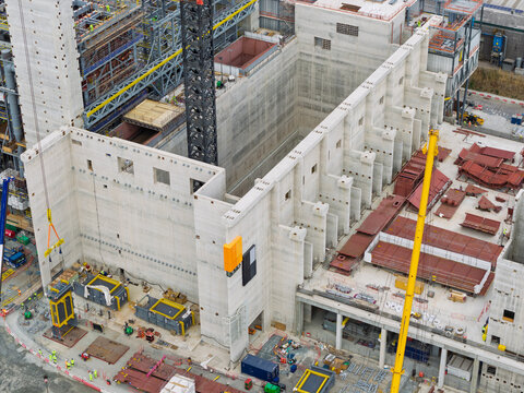 Aerial view of a large industrial construction site featuring massive concrete walls, steel structural elements, and heavy machinery in the United Kingdom.