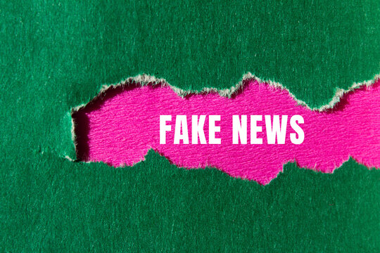 Fake news message written on ripped torn paper background. Conceptual Fake news symbol. Copy space.
