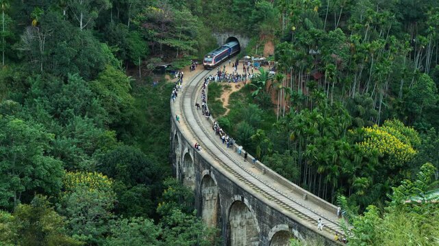 Train coming out of a tunnel and across a stone arch bridge in Ella, Sri Lanka