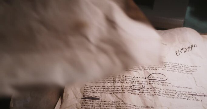 Staged investigator scene showing aged typewritten UFO sketches and declassified archive papers being placed onto a pile of confidential documents.