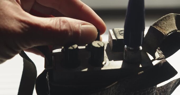 Close up shows a police detective's fingers turning the dials on a vintage walkie talkie, illustrating radio communication, investigation and surveillance technology.