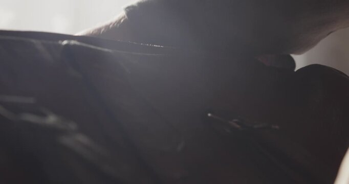 Low angle shows a leather travel bag being zipped closed beside a bright sunlit window before departure, evoking nostalgic travel and leaving home.