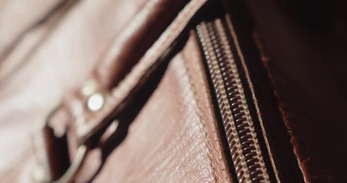 Macro detail shows an old leather travel bag being zipped closed in warm ambient light, creating a nostalgic journey background.