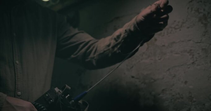 Communication signaller adjusts an antenna on a vintage radio set inside a dark underground bunker, creating a moody cinematic wartime scene.