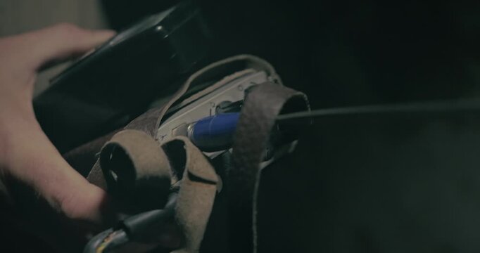 Close-up shows a communications signaller adjusting frequency dials on a retro walkie talkie inside a moody wartime command bunker.