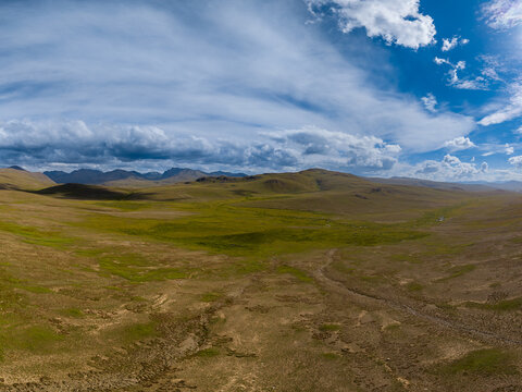 Aerial view of the vast grassy plains and rolling hills of the region under a dramatic cloudy sky, Gilgit-Baltistan, Pakistan.