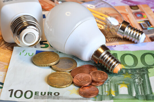 Modern LED light bulbs and coins on Euro banknotes, energy efficiency and electricity cost comparison concept