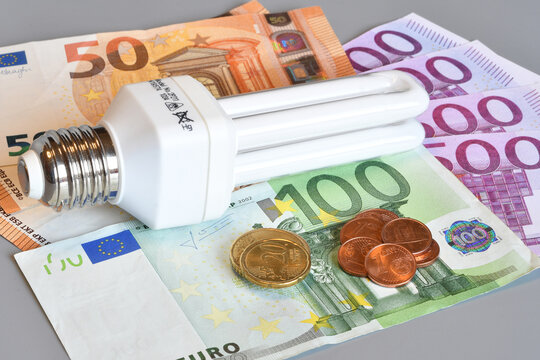 Modern LED light bulbs and coins on Euro banknotes, energy efficiency and electricity cost comparison concept