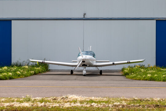 front view of the white small sports aircraft at the aviation hangar