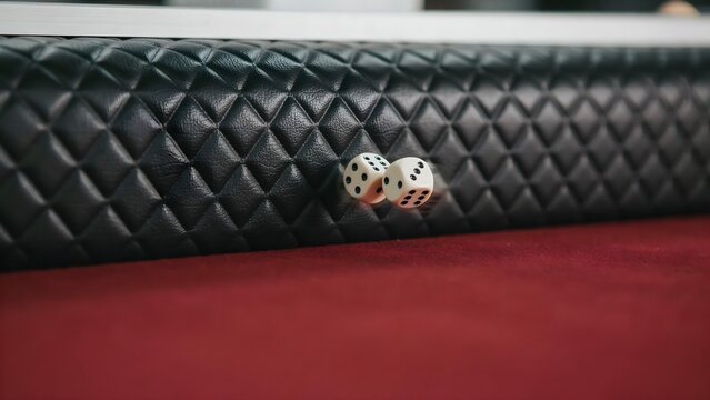 Two Dice Tossed on Red and Black Gaming Table with Quilted Surface