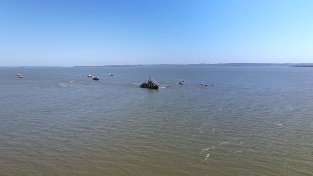 Wide aerial view of Paraguayan naval vessels accompanied by multiple boats navigating the Paran&aacute; River.