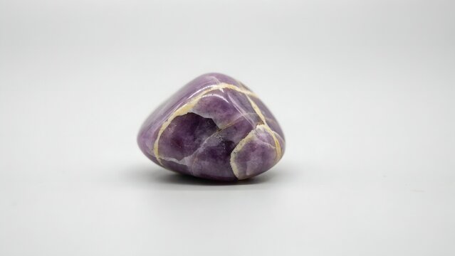 Polished Amethyst Gemstone with Purple and Gold Veins on Plain Background