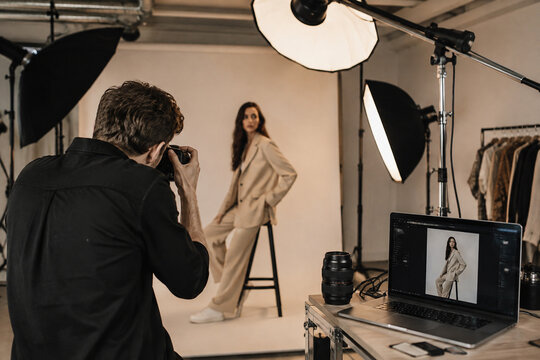 Photographer taking pictures of a female model in a professional photo studio