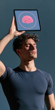 Athletic man holding tablet above head displaying brain illustration in sunlight for health technology cover and cognitive fitness concept