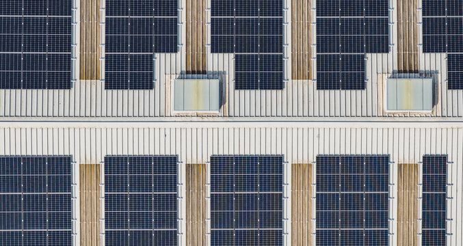 Aerial view of photovoltaic solar panels on an industrial rooftop, showcasing clean energy infrastructure and renewable electricity generation in Le Pouzin, Auvergne-Rhone-Alpes, France.