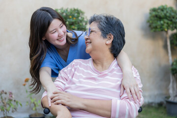 Fototapeta premium Smiling woman hugs older woman in garden during sunny day