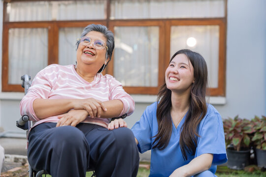 Caregiver talks with senior woman in garden during sunny afternoon