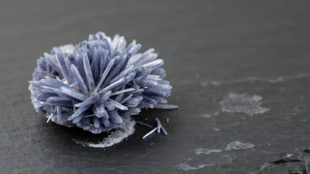 Gray mineral crystal growth on dark stone surface with salt deposits and mineral formation