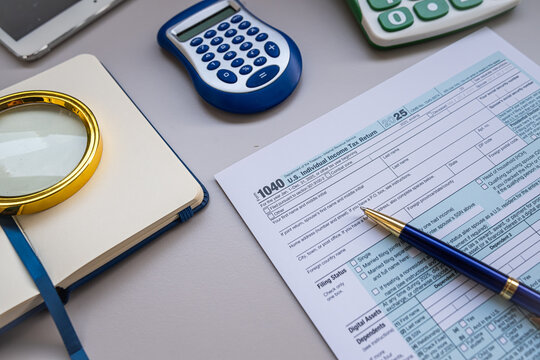 Tax Preparation Workspace with Form 1040 Magnifying Glass Calculators and Pen on Office Desk