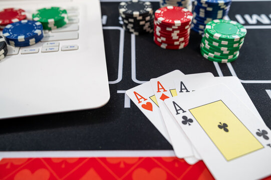 Top View of Laptop Keyboard with Four Aces Poker Cards and Multi Color Tokens for Web Gambling