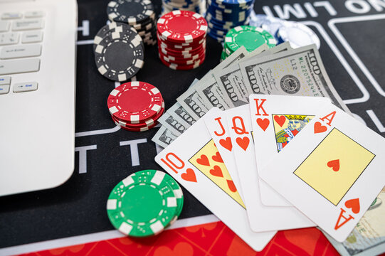 Royal Flush Playing Cards with US Dollar Bills Laptop Keyboard and Chips for Online Poker Game