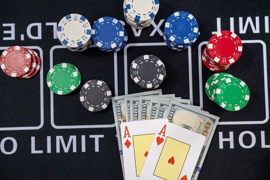 Top View of Hundred Dollar Bills with Pocket Aces Poker Cards and Multi Color Gaming Tokens