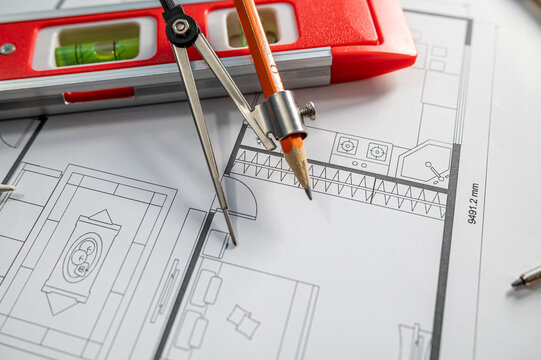 Close up of House Floor Plan Blueprint with Drafting Compass and Red Spirit Level on Desk