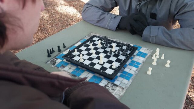 People playing chess game outdoors on a cold day