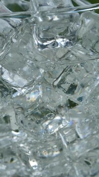 Pouring soda into an ice-filled glass in a bright garden	