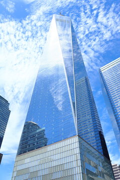 New York, USA - May 26, 2026: One World Trade Center rises above Lower Manhattan, reflecting the blue sky and clouds in its glass facade.
