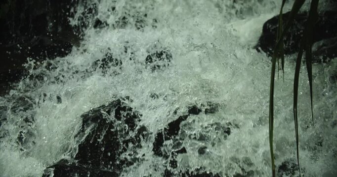  slow motion close-up shot of powerful white foaming water cascading down rocky rapids at Soloka Dare waterfall in Kamrup, Assam, India