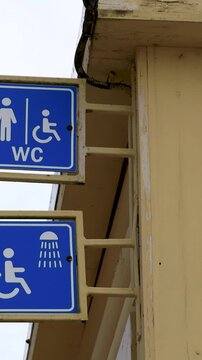 A blue and white street sign on a yellow building. WC, SHOWER ON THE BEACH