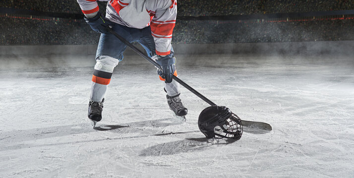 Ice hockey rink arena with professional player shooting the puck with hockey stick.