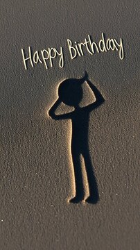 Drawing of person and Happy Birthday text in beach sand.