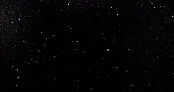Slow motion floating water droplets on a black background. Premium VFX overlay for cinematic compositing, motion graphics, title animations, trailers and professional visual effects.