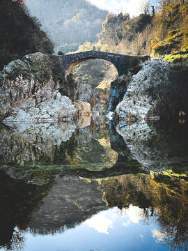 Devil's bridge reflection in ardeche river, france