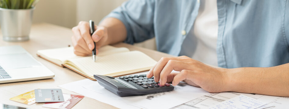 Saving money wealth concept, asian young business man, male using calculator for calculate saving cost, cash finance planning to spend enough money on his income for save money, payment tax, investing