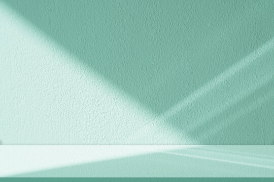 Mint green background with soft shadow and natural light on textured wall and floor, minimal studio interior with abstract leaf shadow, empty space for product display, spring design cosmetic mockup.