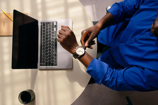Professional Checking Watch While Working On Laptop
