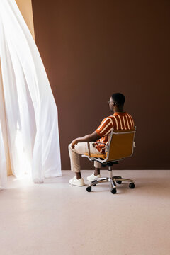 Contemplative Man Sitting in Chair By Window