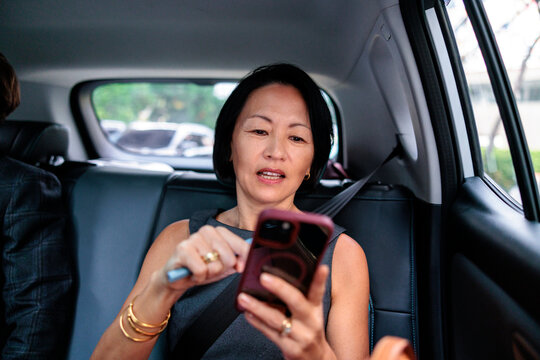 A woman uses her smartphone while riding in a car
