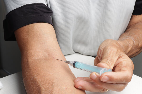 Man Injecting Himself with a Syringe in Arm