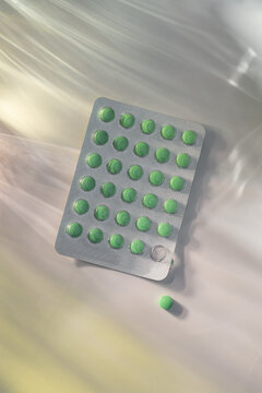 Blister pack of green pills with one loose tablet