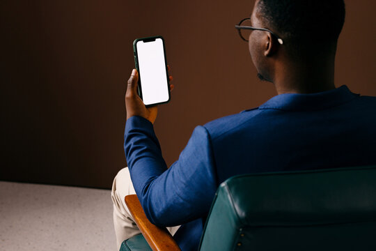 Businessman Sitting in Chair Holding Smartphone With Blank Screen