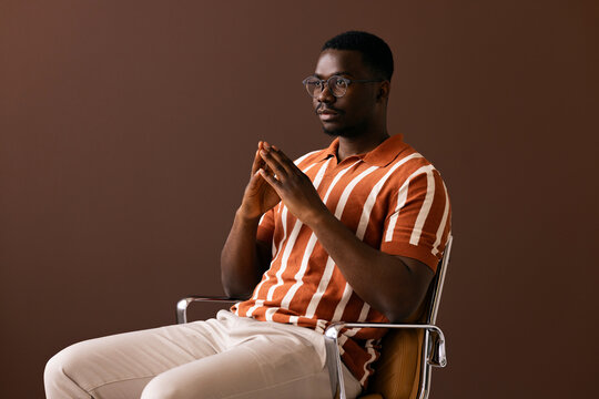 Man Sitting on a Chair against a Brown Background
