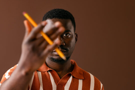 Man Holding Pencil Against Brown Background