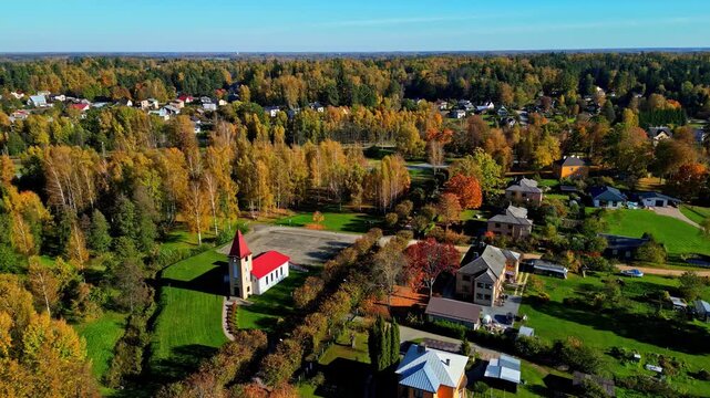 Aerial view of a church surrounded by autumn trees in the town of Kegums, Ogres novads, Latvia.