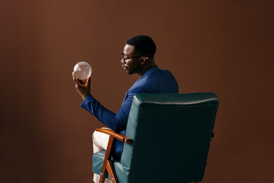Thoughtful Businessman Holding Crystal Ball While Seated