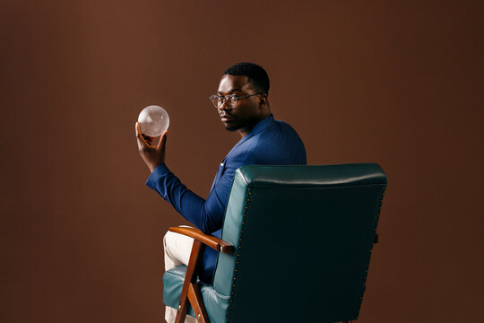 Thoughtful Businessman Holding Crystal Ball in Chair
