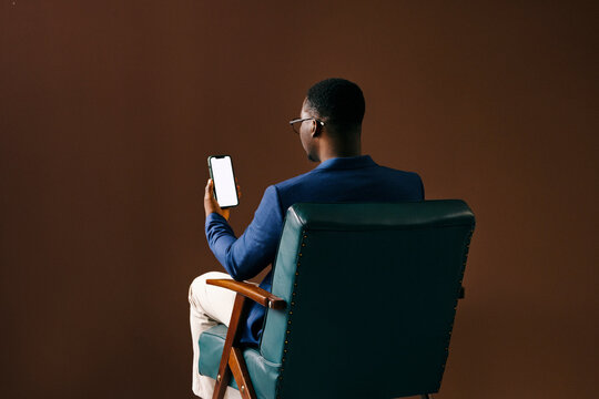 Businessman Sitting in Chair Looking at Smartphone